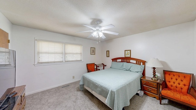 bedroom featuring visible vents, baseboards, ceiling fan, carpet flooring, and a textured ceiling