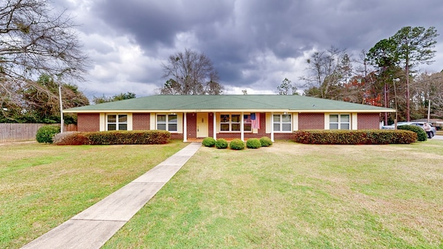 ranch-style house with a front lawn, fence, and brick siding