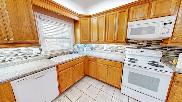 kitchen featuring light tile patterned floors, decorative backsplash, brown cabinets, white appliances, and a sink