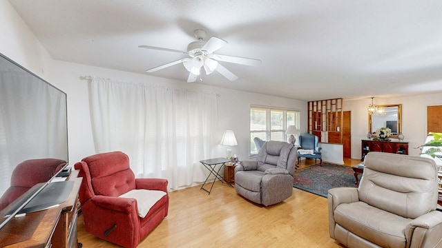 living room with light wood finished floors and ceiling fan with notable chandelier