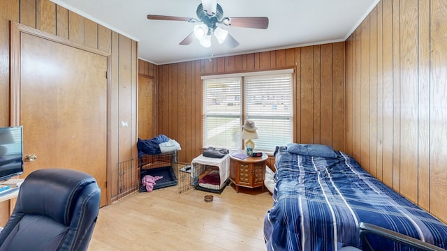 bedroom with wooden walls, light wood-style flooring, and ornamental molding