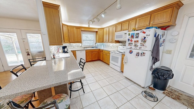 kitchen with white appliances, light tile patterned floors, tasteful backsplash, and a sink