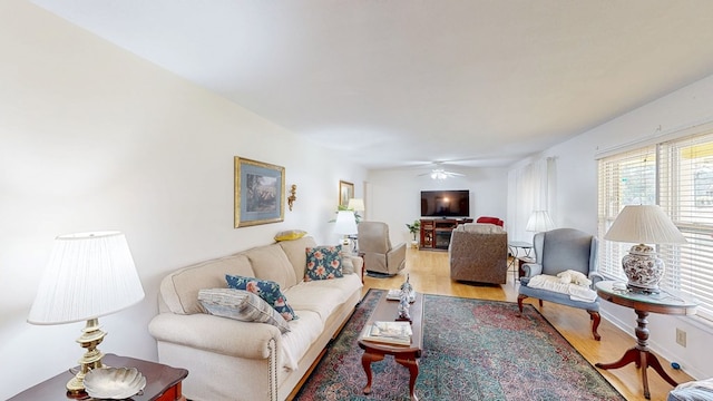 living area with a ceiling fan and wood finished floors