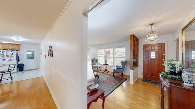 foyer with a notable chandelier, baseboards, and light wood-style floors