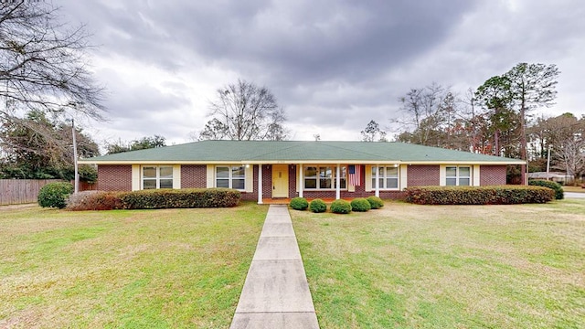 ranch-style home featuring brick siding, a front lawn, and fence