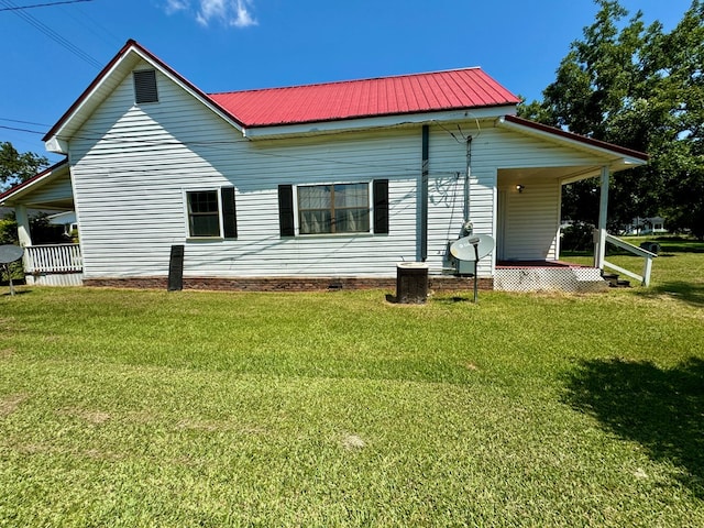 rear view of property featuring a lawn and covered porch