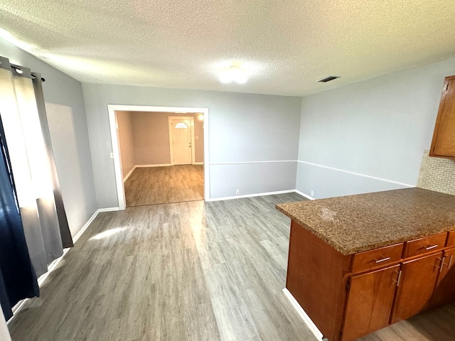 unfurnished dining area featuring light wood-type flooring and a textured ceiling