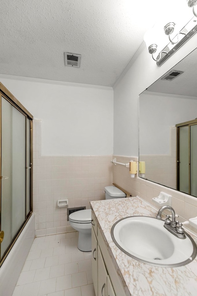 1700 Randall Rd, Dothan, AL 36303 - bathroom with tile walls, vanity, toilet, tile patterned floors, and combined bath / shower with glass door