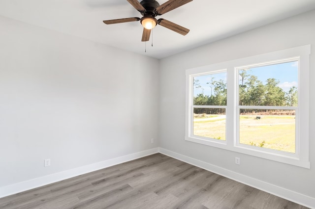 spare room featuring light wood-type flooring, baseboards, and a ceiling fan