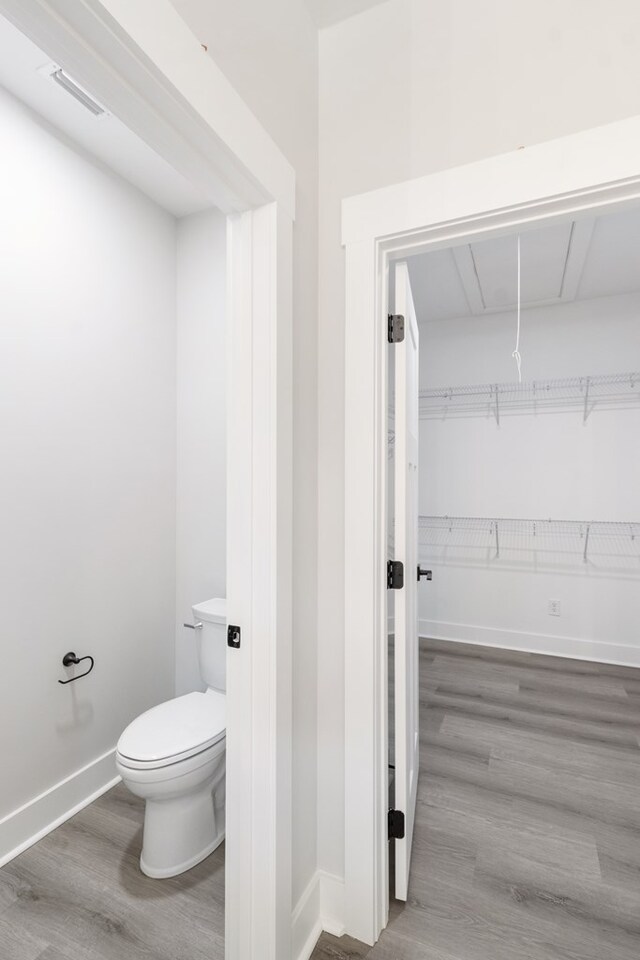 bathroom with toilet, baseboards, visible vents, and wood finished floors