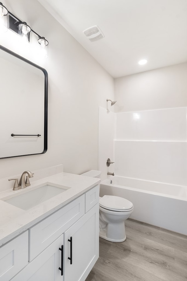 full bath featuring visible vents, toilet, tub / shower combination, vanity, and wood finished floors