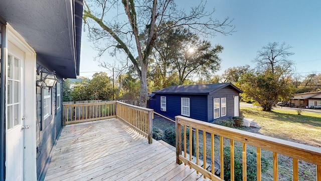 wooden terrace featuring an outbuilding and a lawn