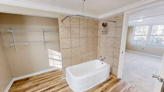 bathroom with hardwood / wood-style floors, crown molding, and tiled shower / bath