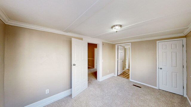 unfurnished bedroom with crown molding and light carpet