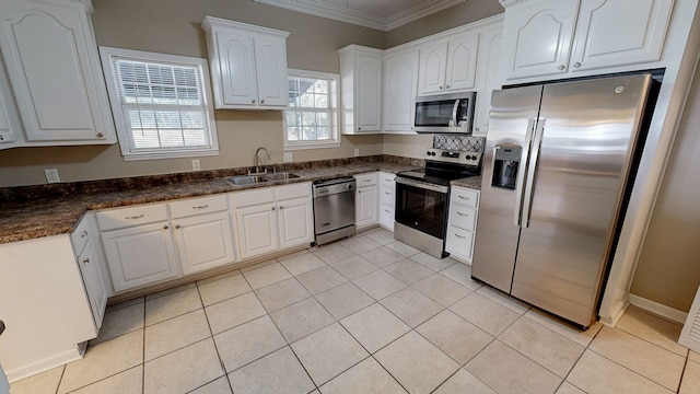 kitchen with light tile patterned floors, stainless steel appliances, crown molding, white cabinets, and sink