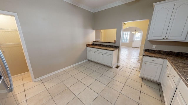 kitchen with light tile patterned flooring, ornamental molding, and white cabinets