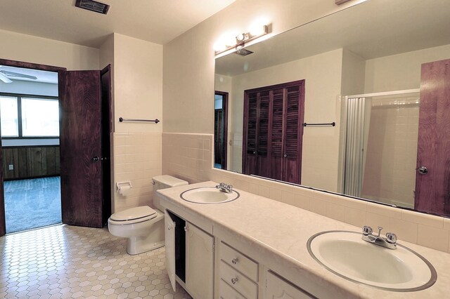 bathroom with vanity, toilet, and tile walls