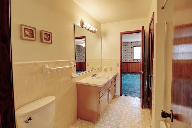 bathroom featuring vanity, tile walls, and toilet