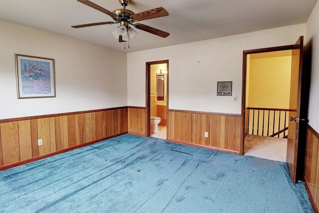 carpeted empty room featuring ceiling fan and wood walls