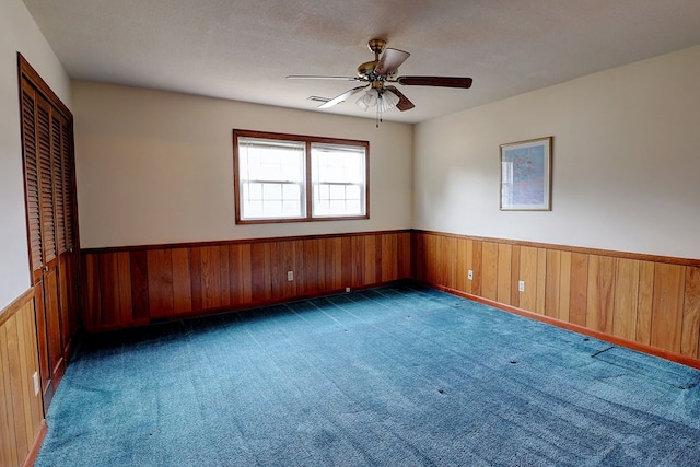 unfurnished room featuring dark colored carpet, a textured ceiling, and wooden walls