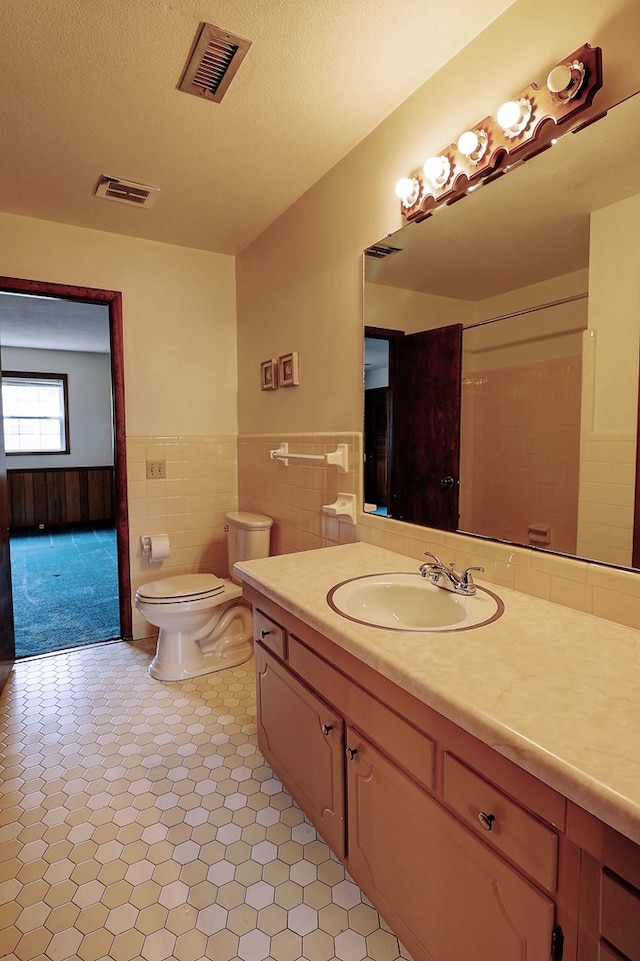 bathroom with vanity, tile walls, toilet, and a textured ceiling