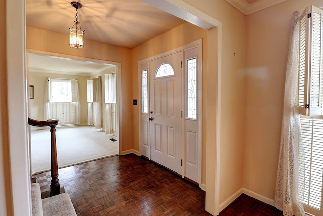 entryway with dark parquet flooring and crown molding