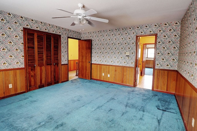 unfurnished bedroom with ceiling fan, light colored carpet, and wood walls