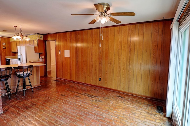 kitchen with a breakfast bar, ornamental molding, kitchen peninsula, white fridge with ice dispenser, and ceiling fan