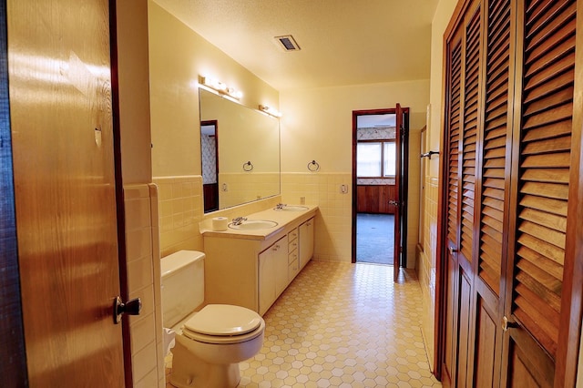 bathroom with tile walls, vanity, a textured ceiling, and toilet