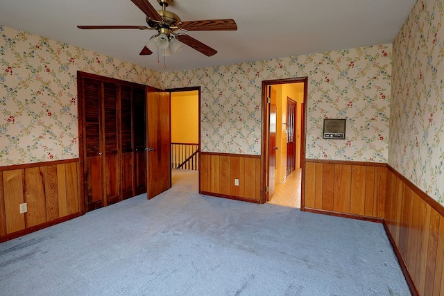 spare room featuring ceiling fan, light carpet, and wood walls