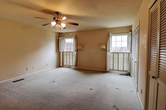 spare room featuring light carpet, ceiling fan, and a textured ceiling