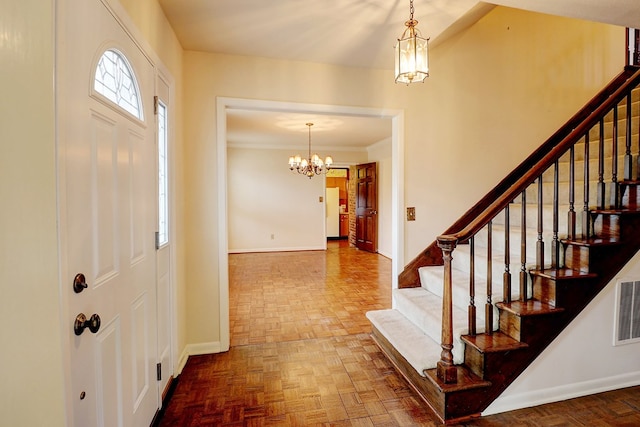 foyer entrance with parquet floors, crown molding, and a chandelier