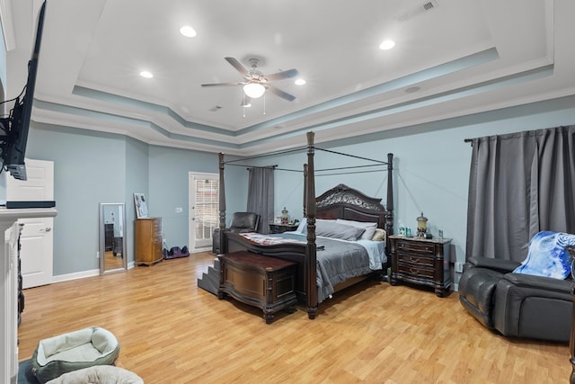 bedroom featuring ornamental molding, a tray ceiling, ceiling fan, and light hardwood / wood-style floors