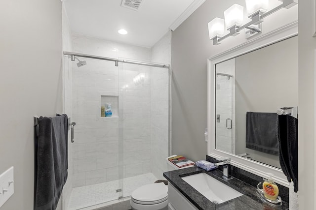 bathroom featuring vanity, toilet, a shower with shower door, and crown molding