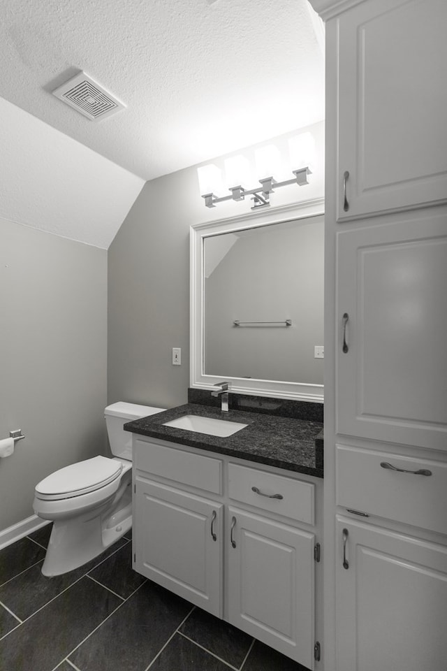 bathroom featuring a textured ceiling, vanity, tile patterned flooring, toilet, and lofted ceiling