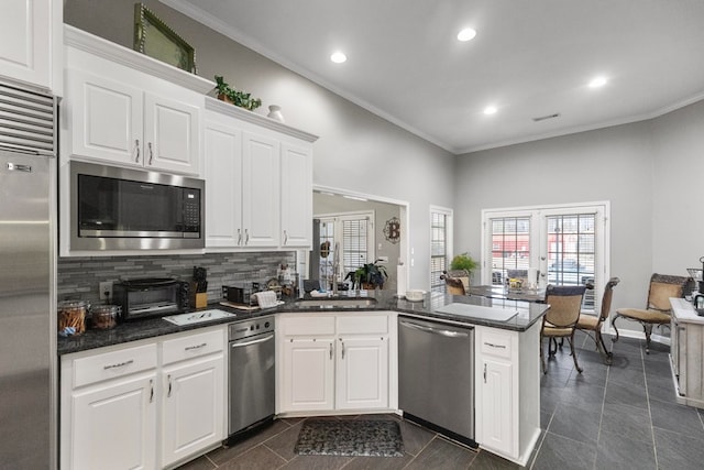 kitchen featuring kitchen peninsula, white cabinetry, decorative backsplash, and appliances with stainless steel finishes