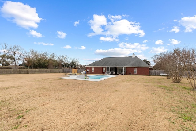 back of house featuring a yard, a fenced in pool, a patio area, and a sunroom