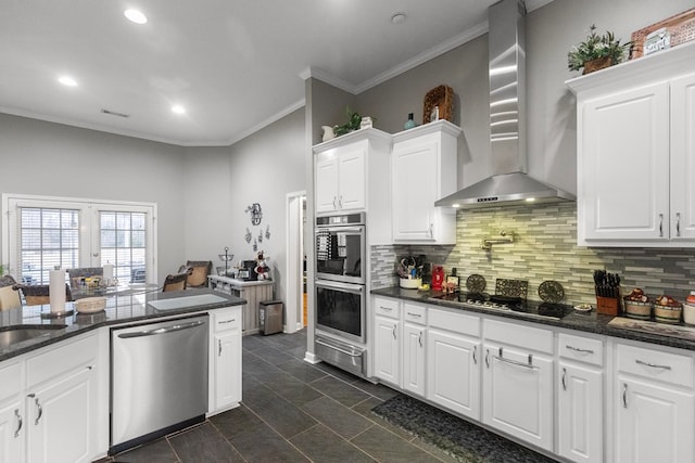 kitchen featuring backsplash, white cabinets, crown molding, wall chimney exhaust hood, and appliances with stainless steel finishes