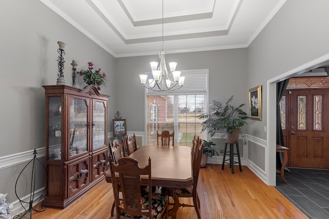 dining room with light hardwood / wood-style flooring, crown molding, a tray ceiling, and a chandelier