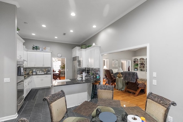 kitchen with kitchen peninsula, decorative backsplash, white cabinets, and ornamental molding