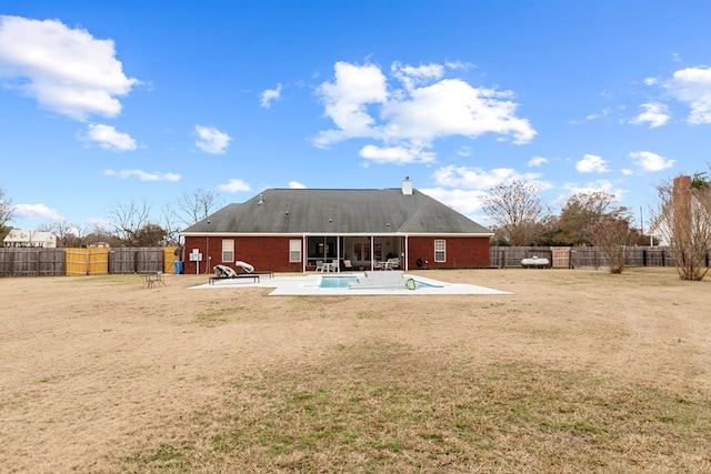 rear view of house featuring a patio area, a fenced in pool, and a yard