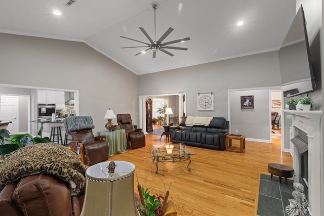 living room with a fireplace, wood-type flooring, high vaulted ceiling, and ornamental molding