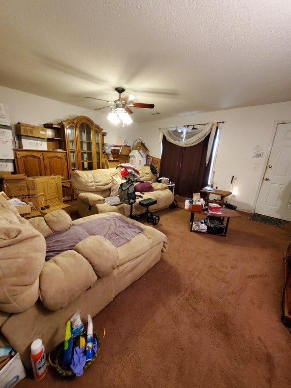 living room featuring ceiling fan, carpet floors, and a textured ceiling