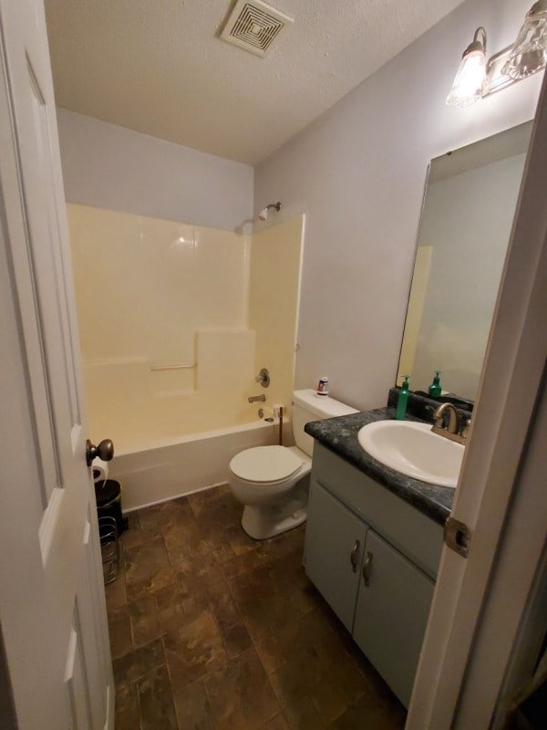 full bathroom featuring vanity, a textured ceiling, toilet, and shower / bath combination