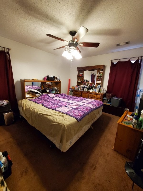 carpeted bedroom with ceiling fan and a textured ceiling