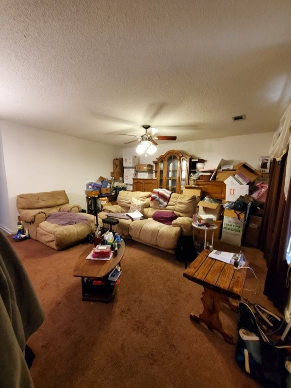 carpeted living room featuring ceiling fan and a textured ceiling
