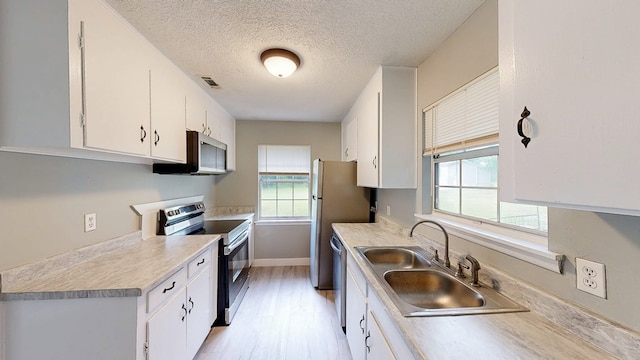 806 County Road 23, Skipperville, AL 36374 - kitchen featuring appliances with stainless steel finishes, light wood-style flooring, white cabinetry, light countertops, and a textured ceiling