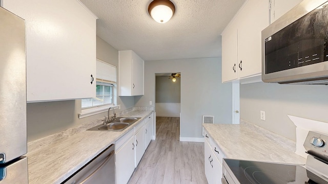 806 County Road 23, Skipperville, AL 36374 - kitchen featuring stainless steel appliances, light wood-type flooring, a textured ceiling, light countertops, and white cabinetry