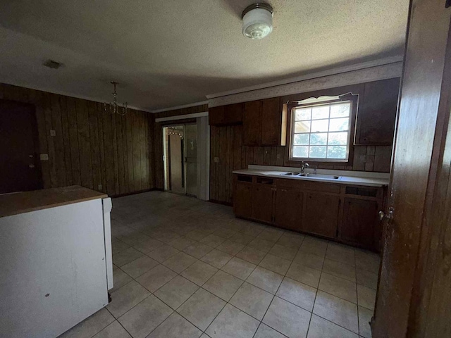 230 Sharon Ct, Ozark, AL 36360 - kitchen featuring wood walls, light countertops, light tile patterned floors, and a textured ceiling