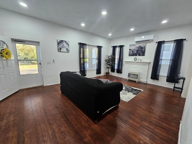 living room with a wall mounted AC, recessed lighting, wood-type flooring, baseboards, and a brick fireplace